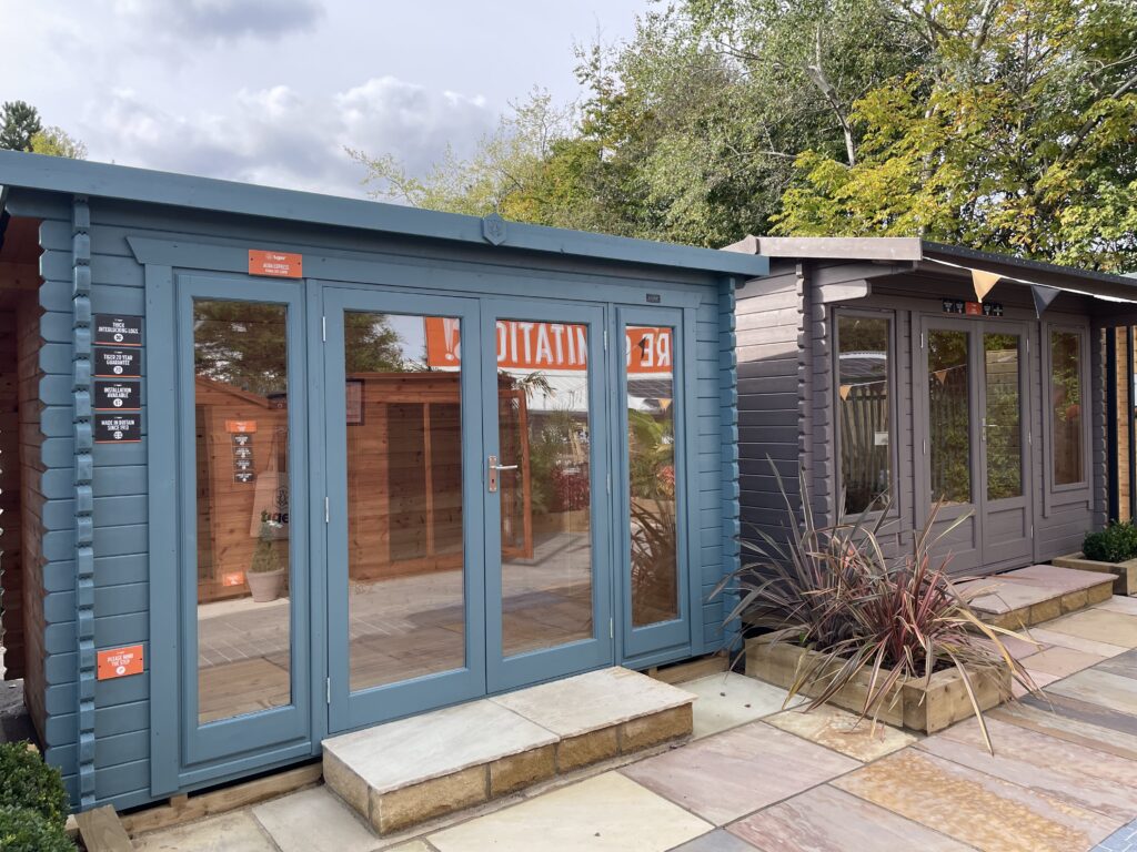 Front exterior view of Tiger Aura 44 mm Log Cabin at Tong show site with full-height glazed doors and interlocking log walls.