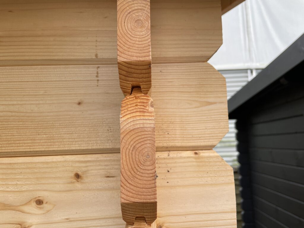 Close-up of the Tiger Persian 28 mm Log Cabin corner joint at the Otley show site showing the natural timber finish and interlocking tongue-and-groove logs.