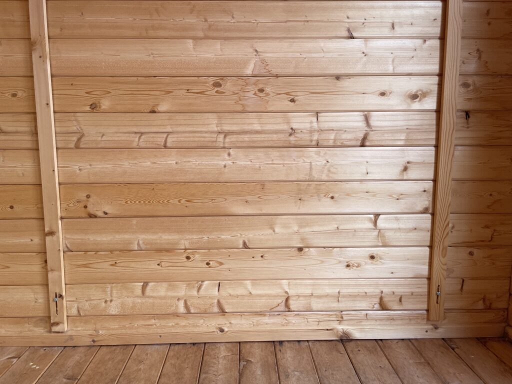 Close-up interior wall view of Tiger Rho 44 mm Log Cabin at Horsforth show site showing tongue-and-groove timber panelling.