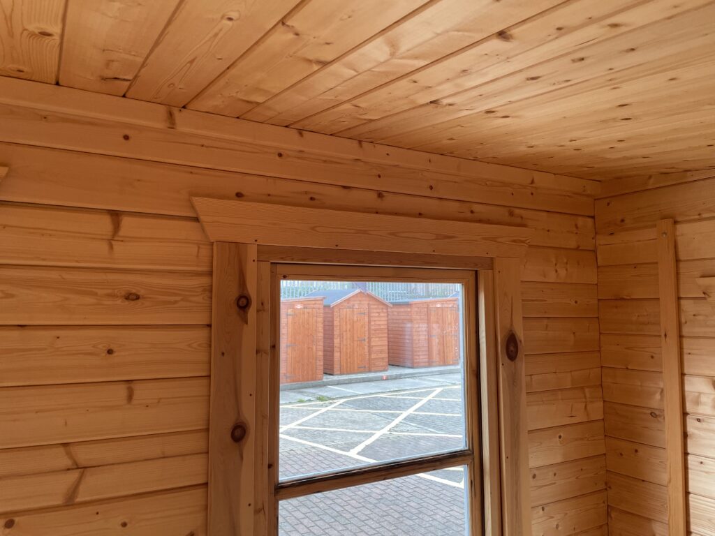 Interior close-up of Tiger Rho 44 mm Log Cabin at Horsforth show site showing timber window frame and ceiling panelling.