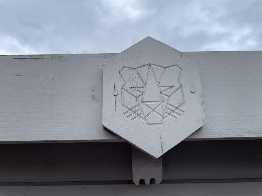 Close-up of Tiger Rho 44 mm Log Cabin badge showing geometric tiger head emblem at Horsforth show site.