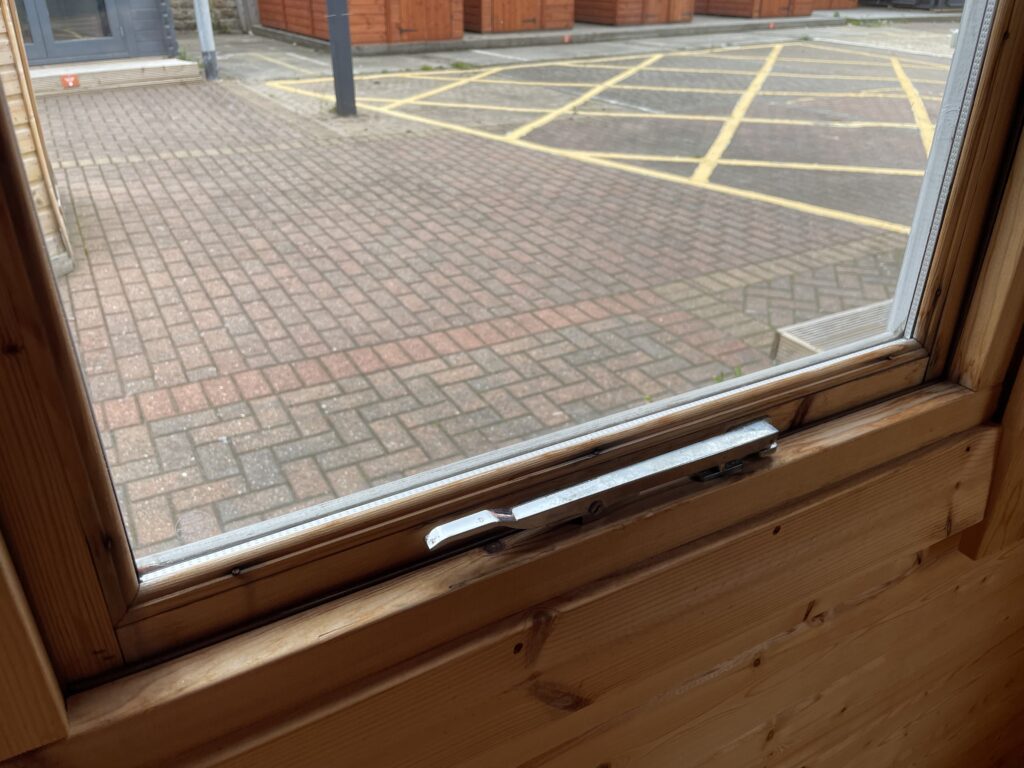 Close-up of Tiger Rho 44 mm Log Cabin timber window frame with metal latch handle detail at Horsforth show site.