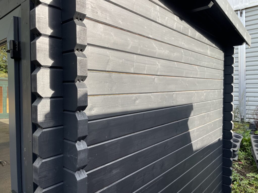 Close-up view of Tiger Serena 44 mm Log Cabin interlocking corner joint with dark-stained timber cladding at Otley show site.