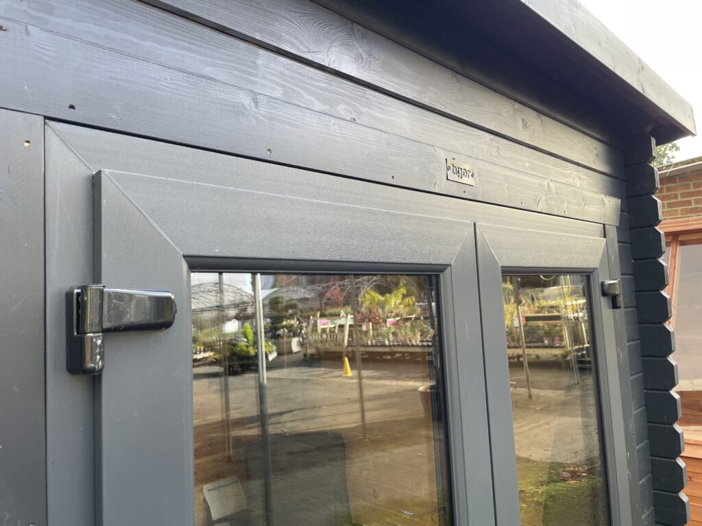 Close-up view of Tiger Serena 44 mm Log Cabin uPVC door frame with dark anthracite finish and reflective glazing at Otley show site.