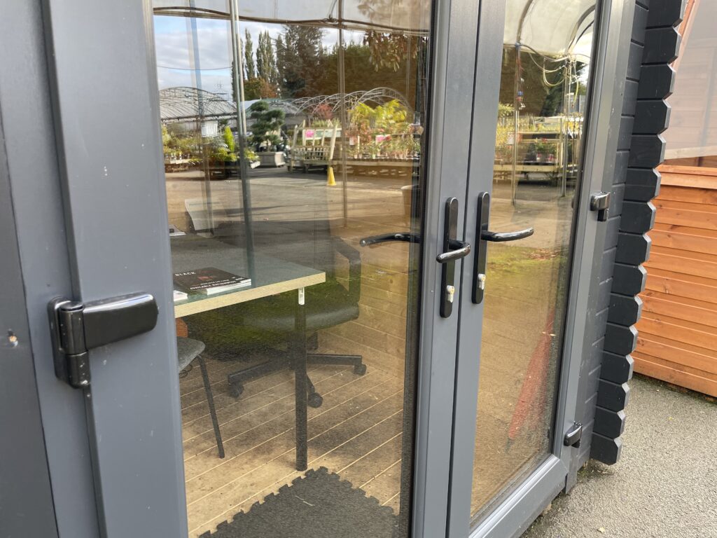 Close-up of Tiger Serena 44 mm Log Cabin anthracite uPVC double doors with black handles and locking mechanism at Otley show site.