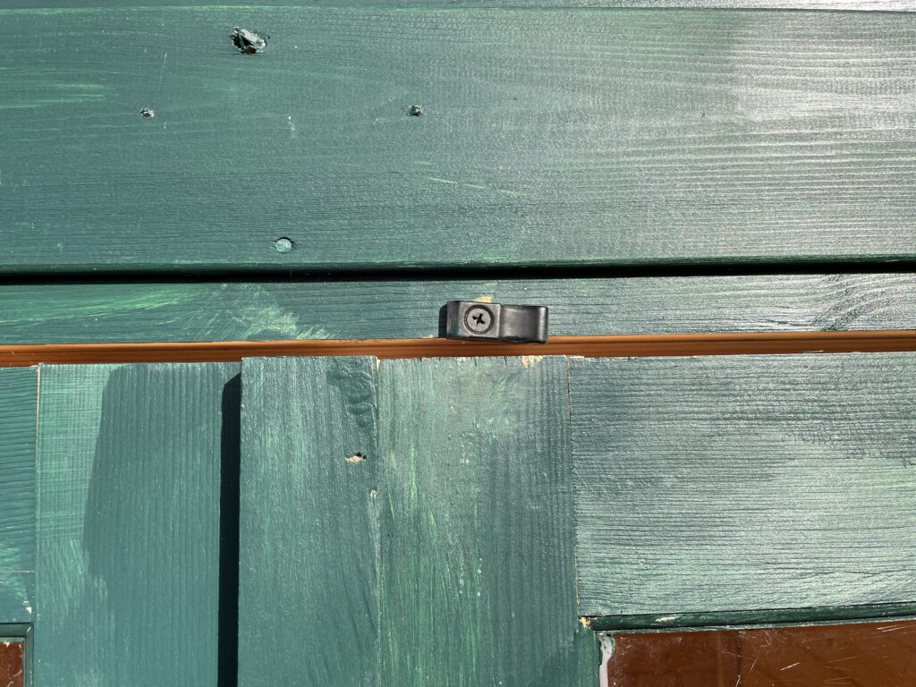 Close-up of the TigerFlex Moda 19mm Log Cabin door catch at the Otley show site, showing the small metal retaining clip and precision join between the door frame and wall cladding.