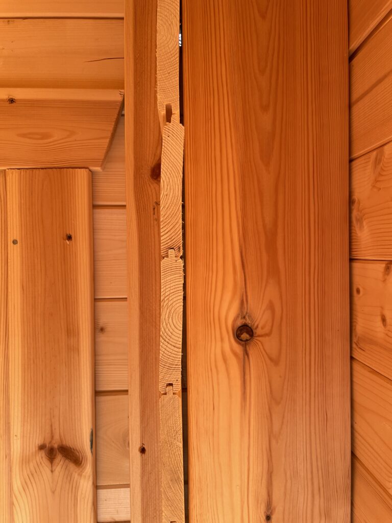 Close-up of the TigerFlex Moda 19 mm Log Cabin interior post joint at the Otley show site showing the tongue-and-groove timber connection and natural wood grain detail.