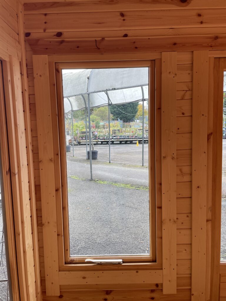 Interior view showcasing a full-pane window in a wooden cabin