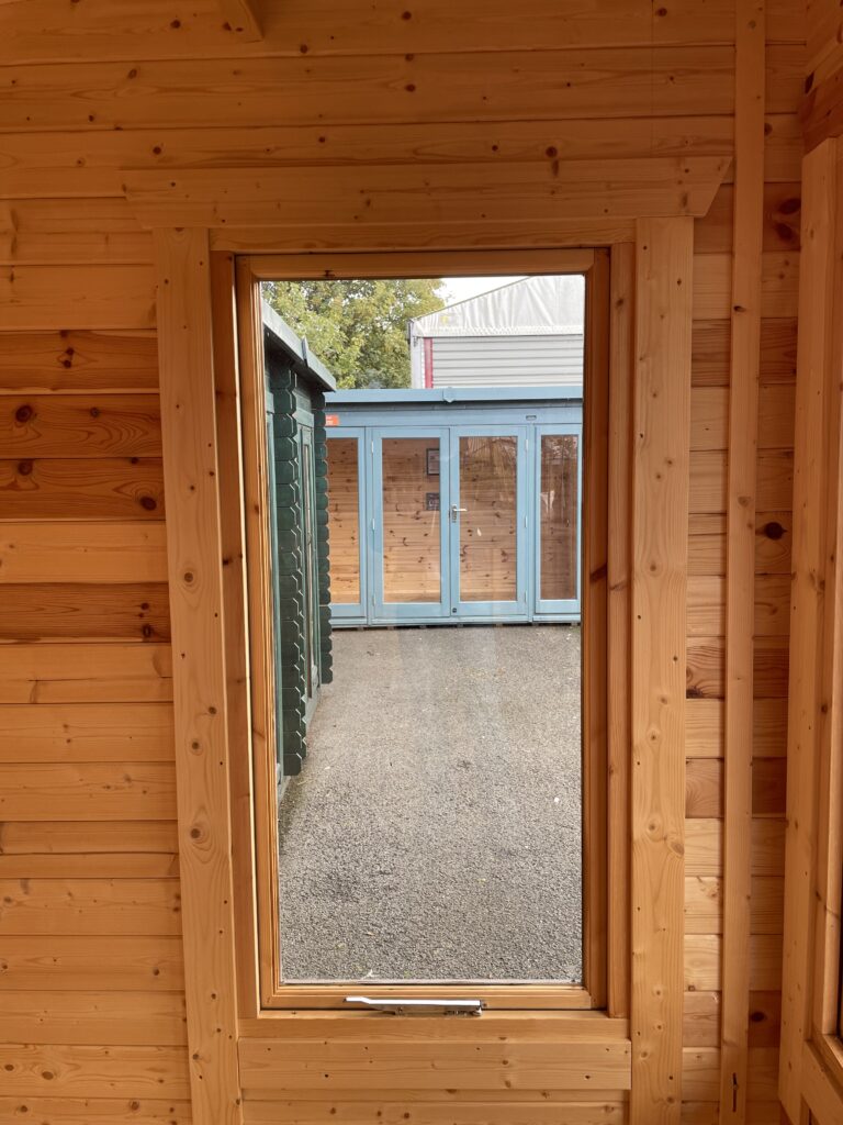 Interior view showcasing a full-pane window in a wooden garden building