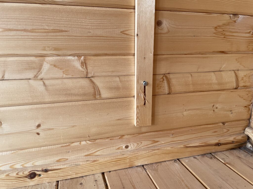 Interior wall of a garden building featuring wooden cladding and joinery