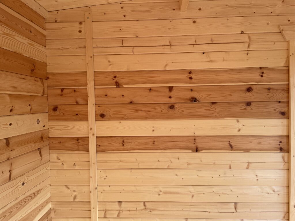 Interior wall detail of a garden building featuring smooth timber cladding