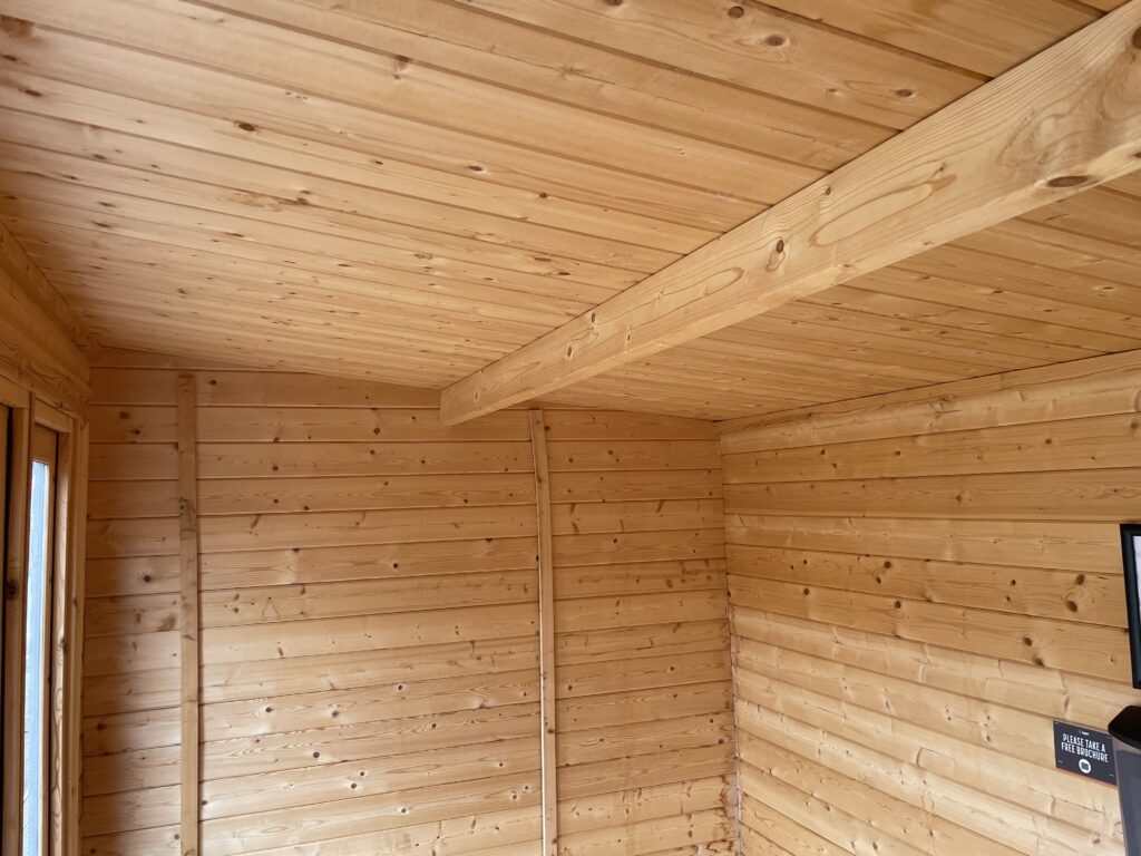 Interior view showcasing a pent roof with wooden beams and cladding