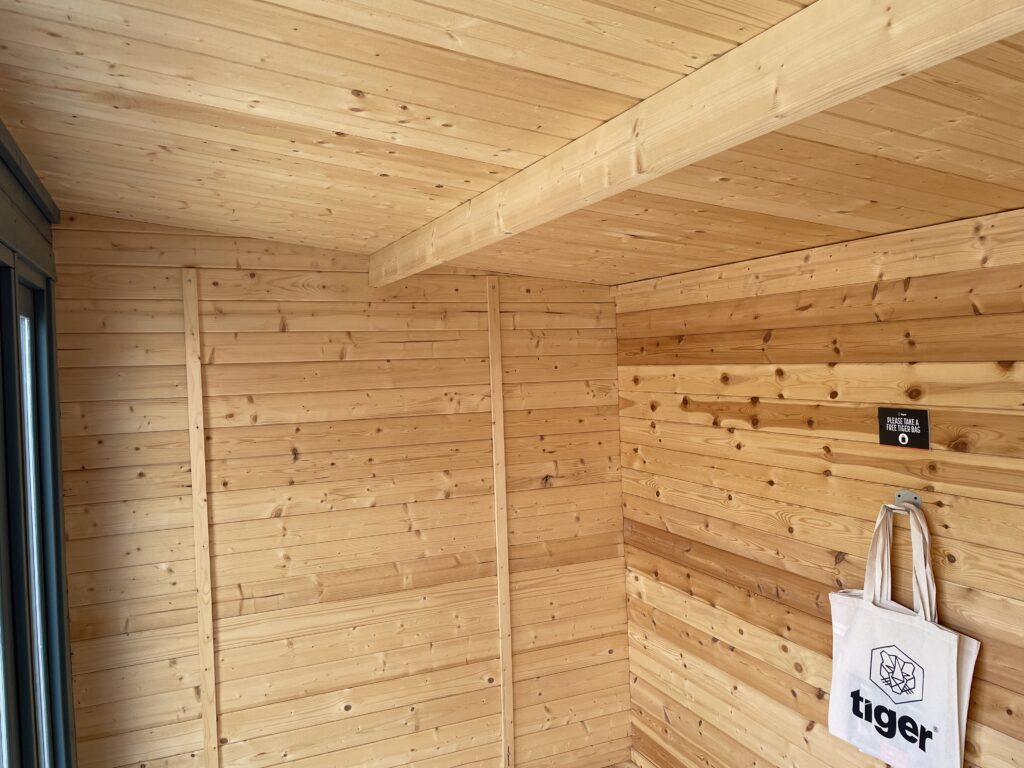Interior view showcasing timber walls and ceiling beams of a garden building