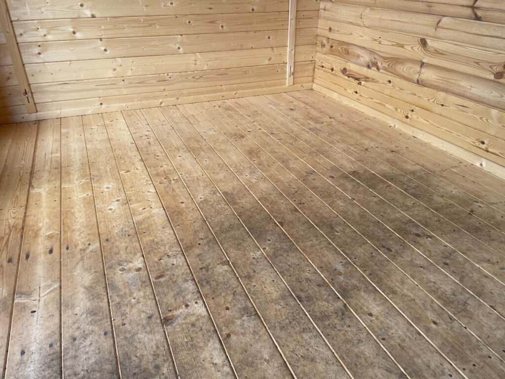 Timber floor of a garden building showing natural wood grain and slight wear