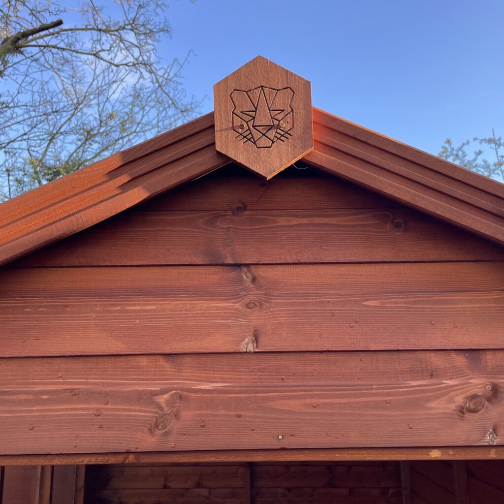 Apex of a garden building with a logo and wooden cladding