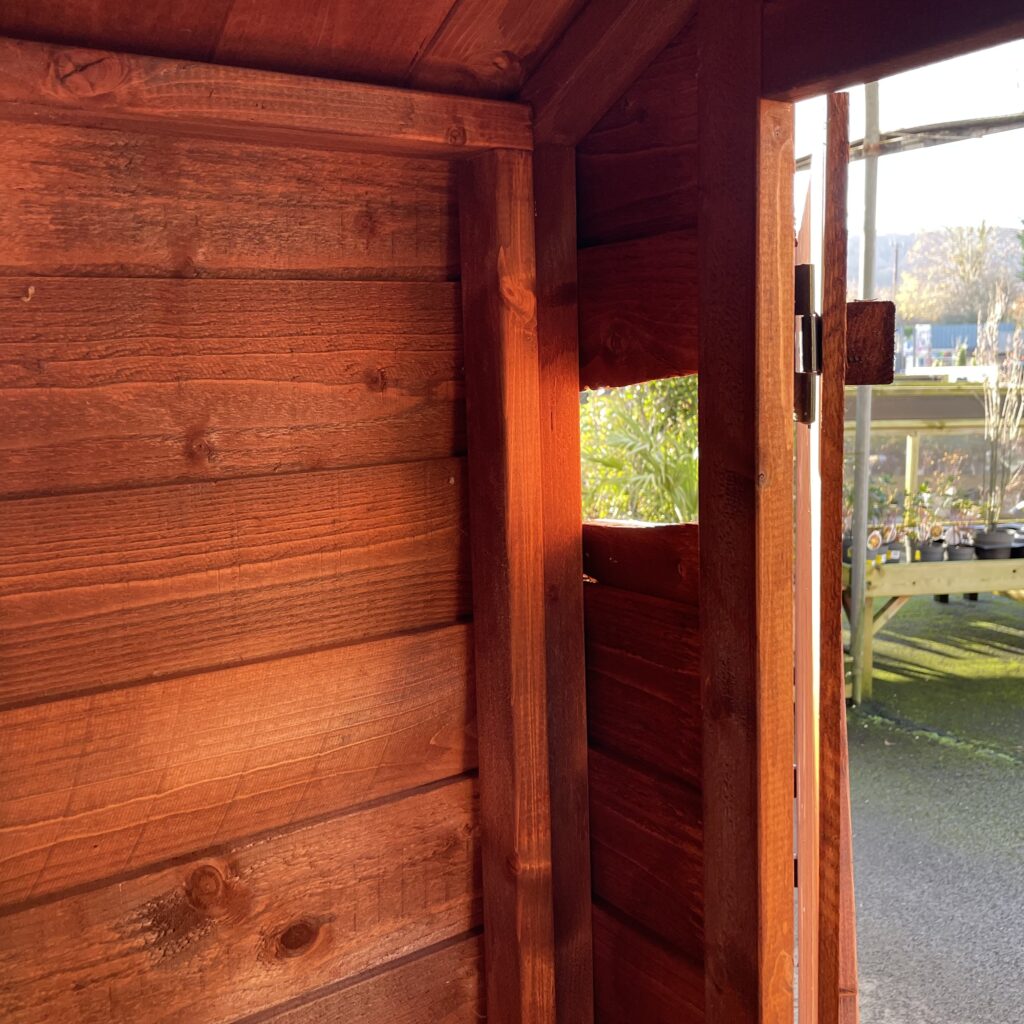 Interior of a wooden garden building showcasing rich brown timber