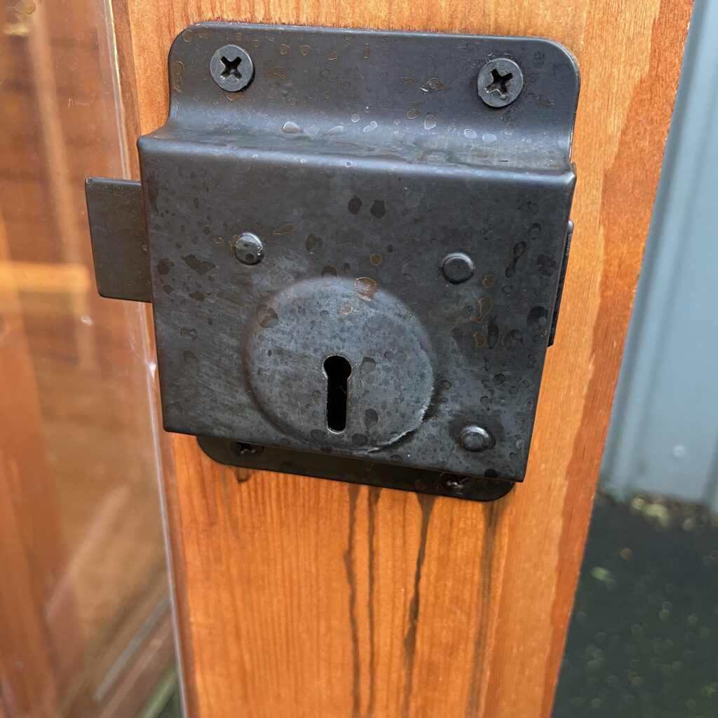 Close-up of a metal door lock on a wooden garden building