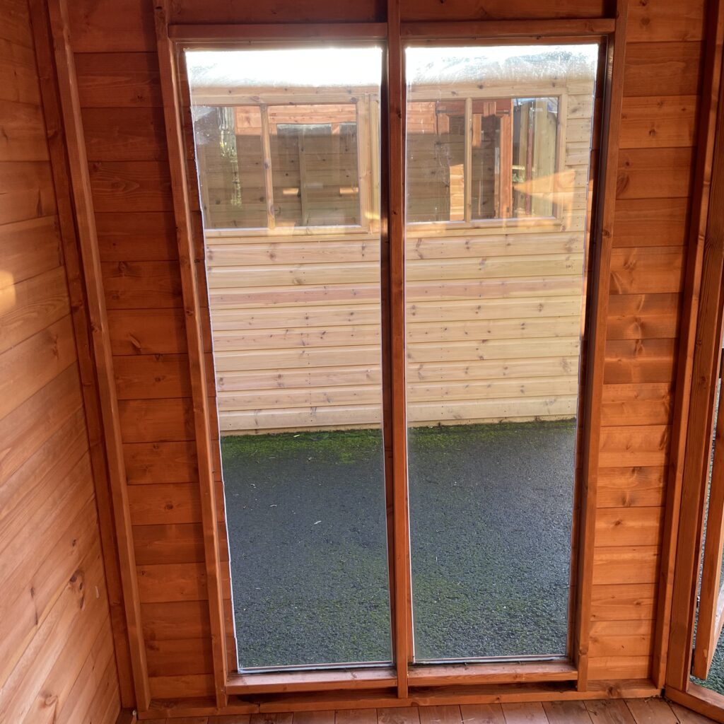 Interior view of the Tiger Corner Summerhouse featuring double doors and wooden cladding
