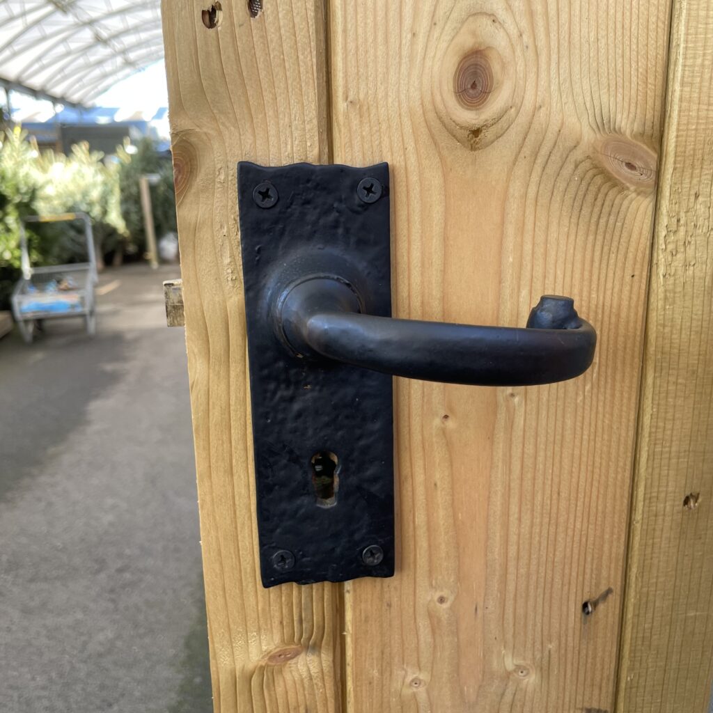 Close-up of a sturdy black door handle on a wooden shed