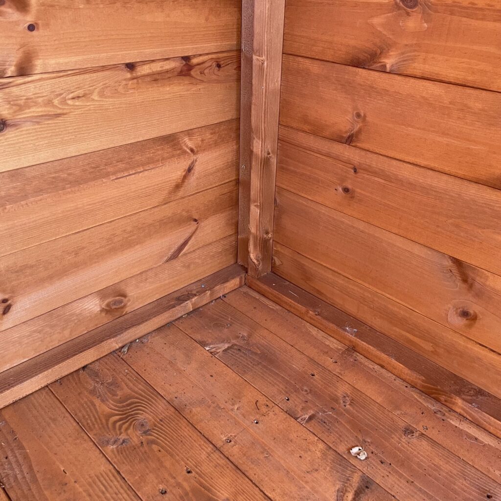 Interior view of a wooden garden building corner with cladding and floor