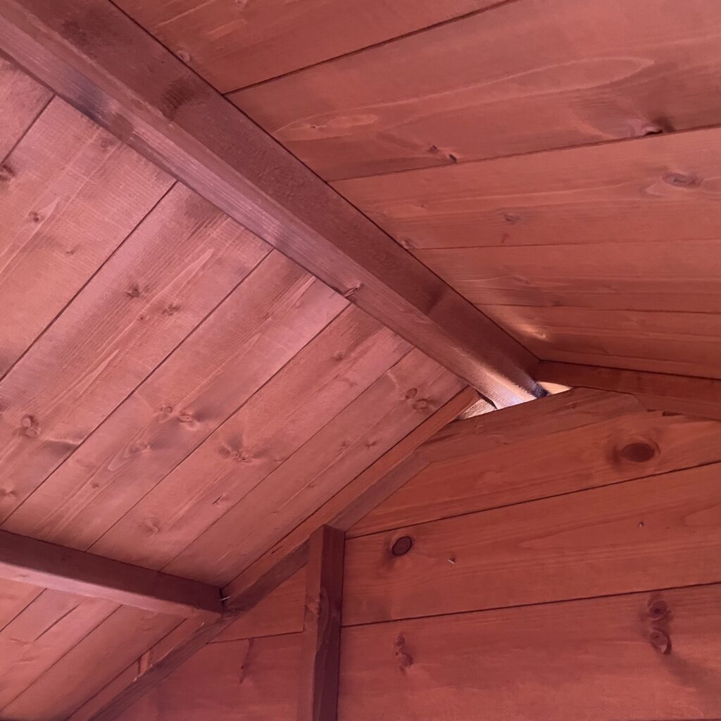Interior view of a log cabin ceiling showcasing wooden beams and cladding