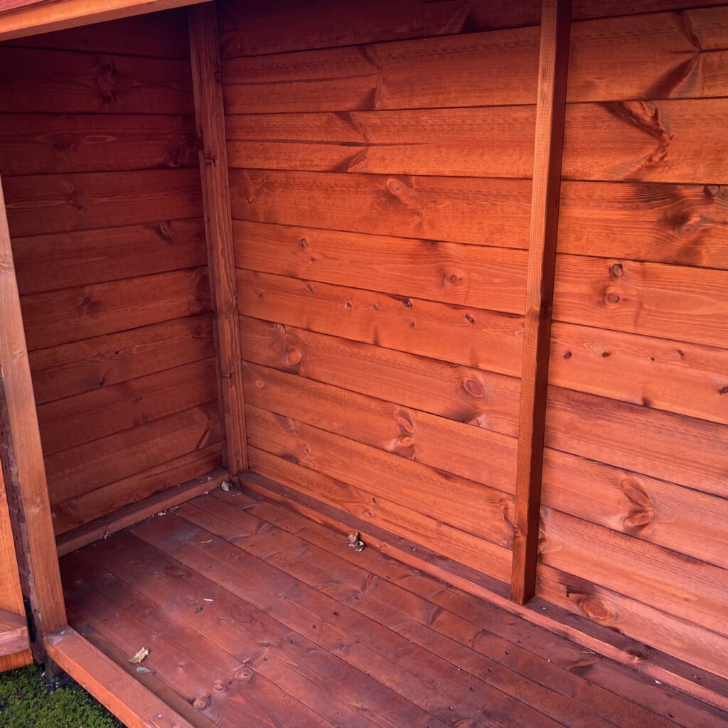 Interior view of a wooden garden building floor showing tongue and groove construction