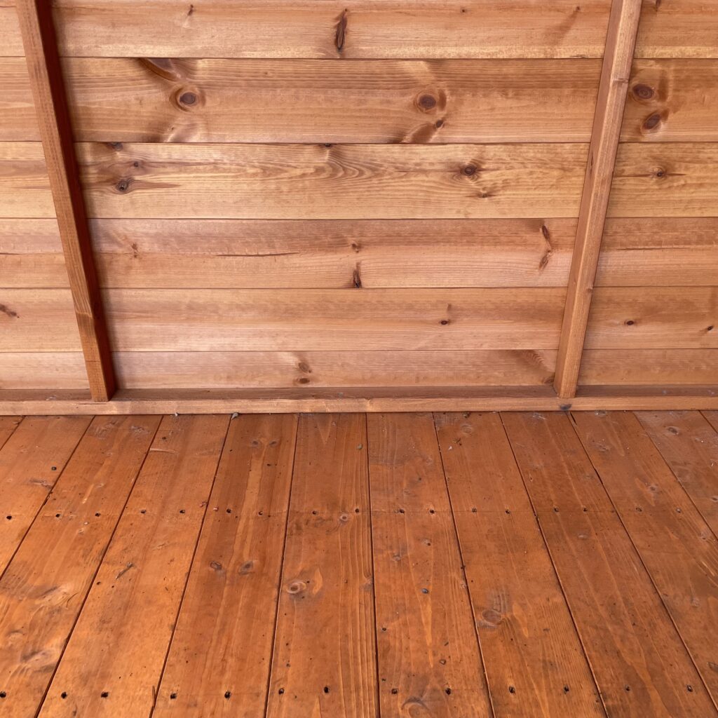 Interior view of a wooden floor and wall cladding in a garden building