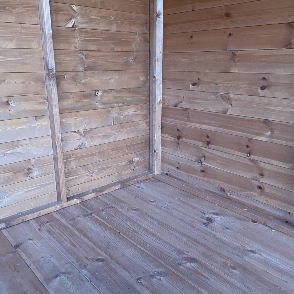Interior view of the Tiger Loglap Mini-Barn with wooden walls and floor