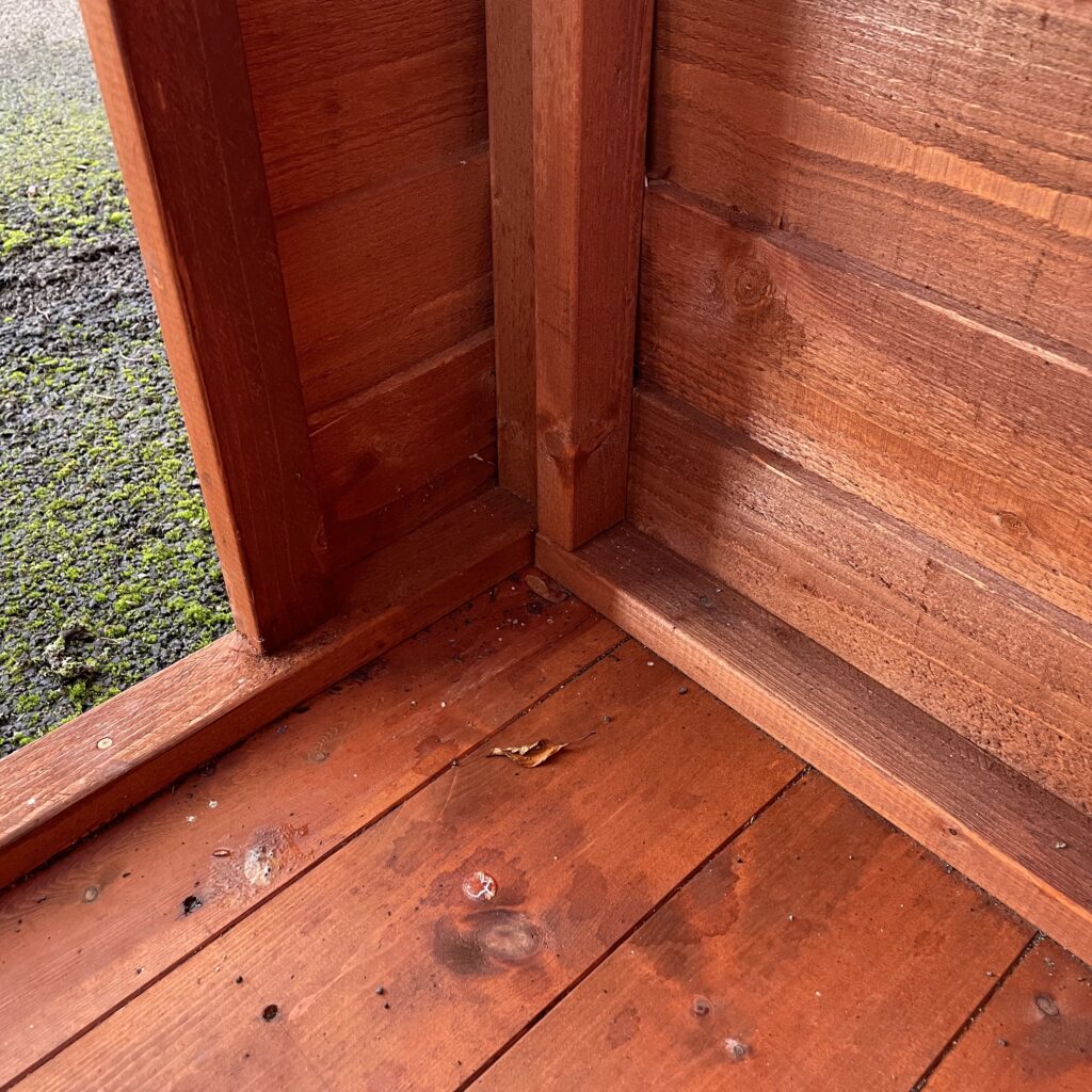 Interior corner of a Tiger Overlap Apex Shed showcasing wooden cladding and floor