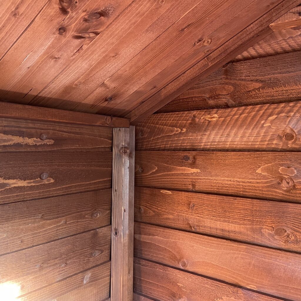 Interior corner of a Tiger Overlap Apex Shed displaying wooden cladding and support beam