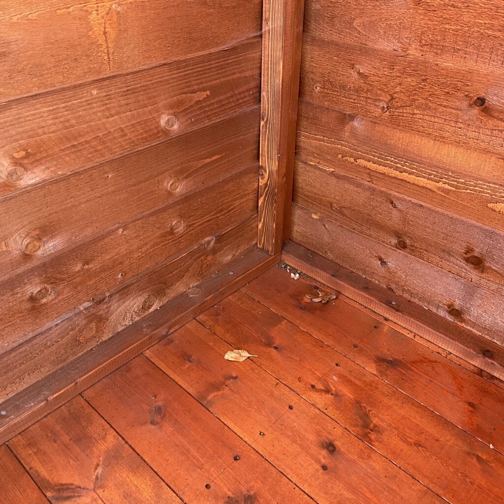 Interior corner of a Tiger Overlap Apex Shed showcasing wooden walls and floor