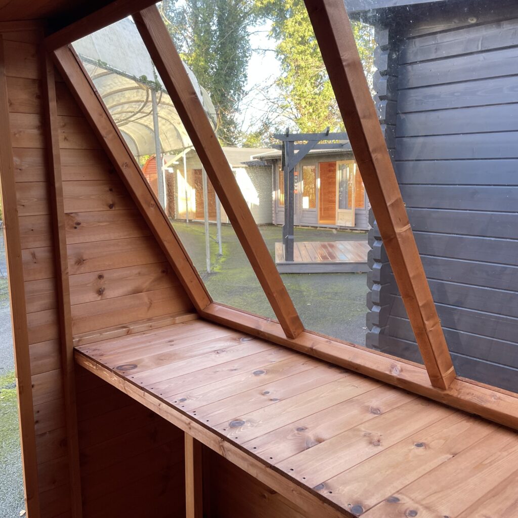 Interior view of a Tiger Potting Shed with wooden shelves and angled windows