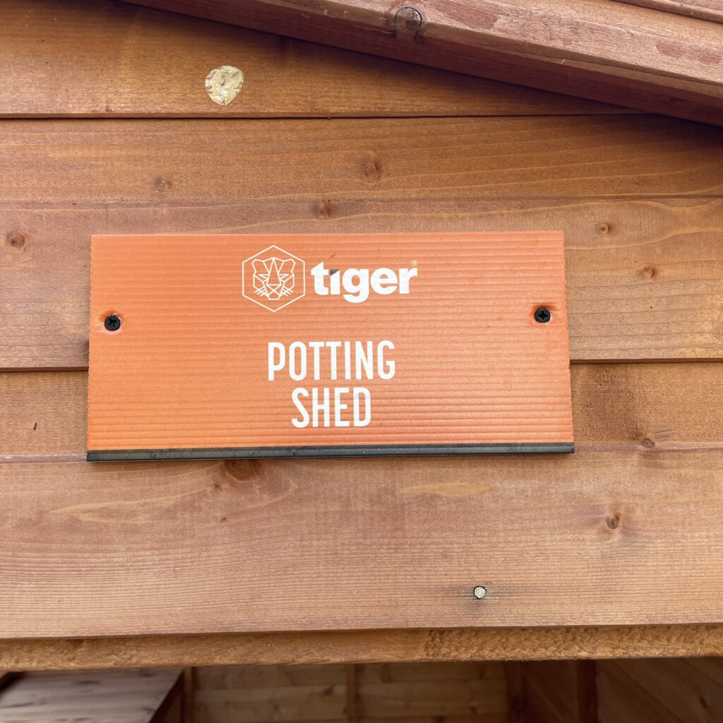 Signage displaying 'Potting Shed' on a Tiger garden building