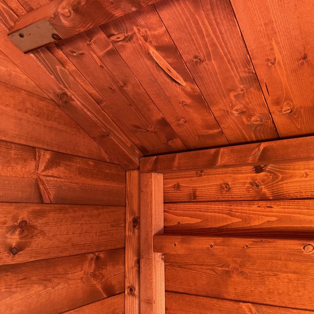 Interior of a garden building with red wooden cladding and ceiling