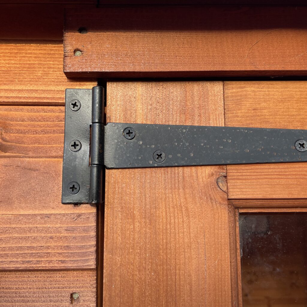 Close-up of a sturdy hinge on a wooden door of a summerhouse