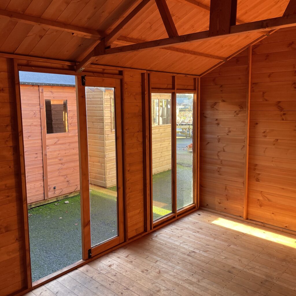 Interior of the Tiger Retreat Contemporary Summerhouse featuring large glass doors and wooden walls