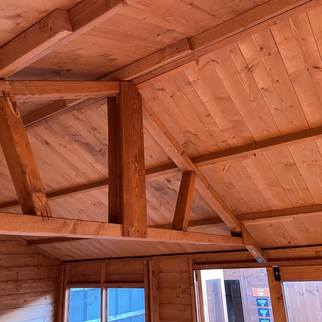Interior view of the Tiger Retreat Contemporary Summerhouse showing wooden beams and ceiling