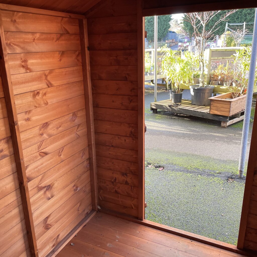 Interior view of a Tiger Shiplap Apex Shed showing wooden walls and an open door