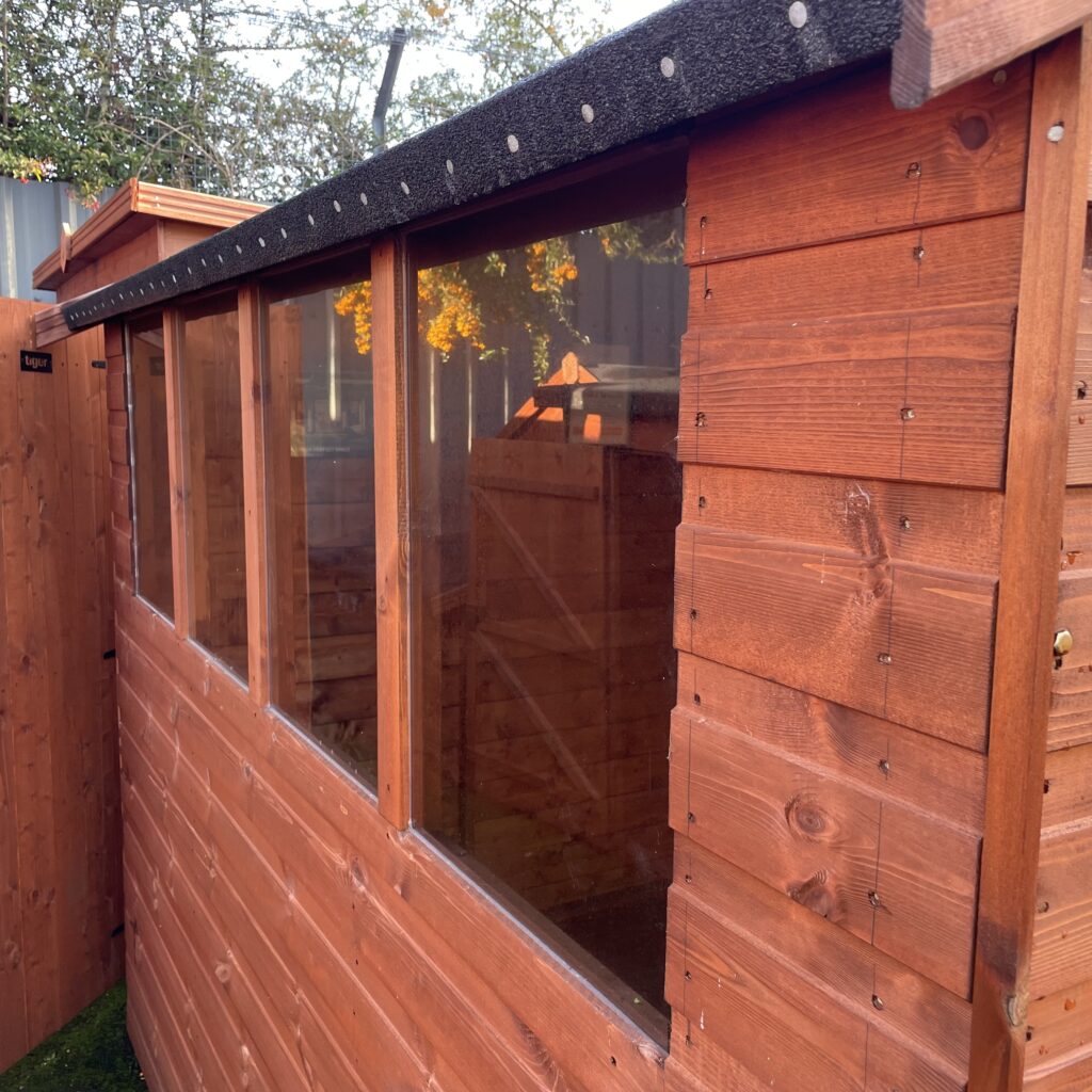 Side view of a garden building with large windows and wooden cladding