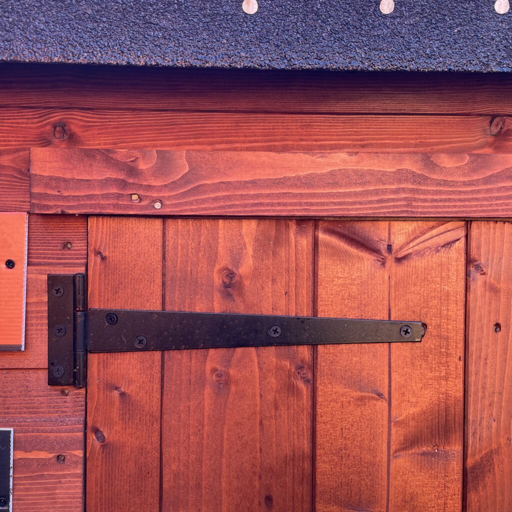 Close-up of the sturdy door hinge and latch on a garden storage unit