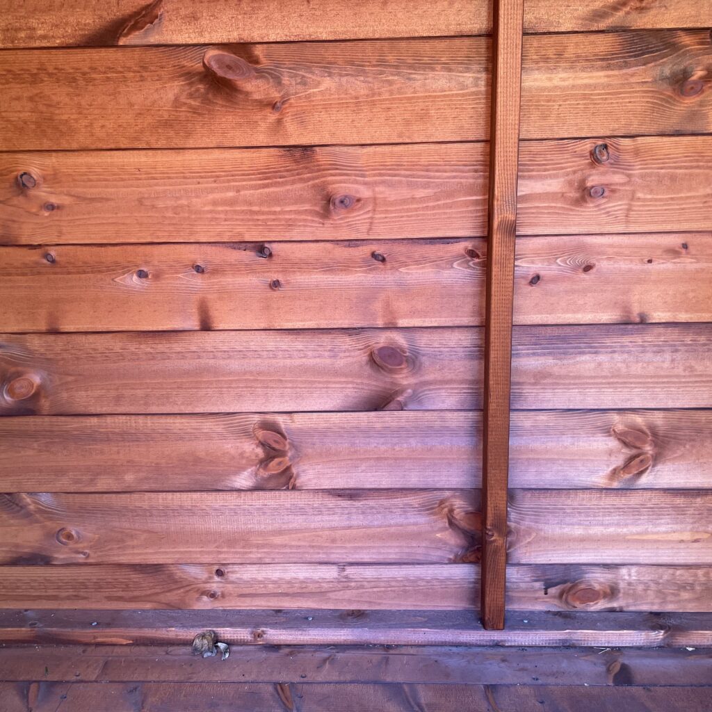 Wooden wall panels of a garden building with visible grain and knots