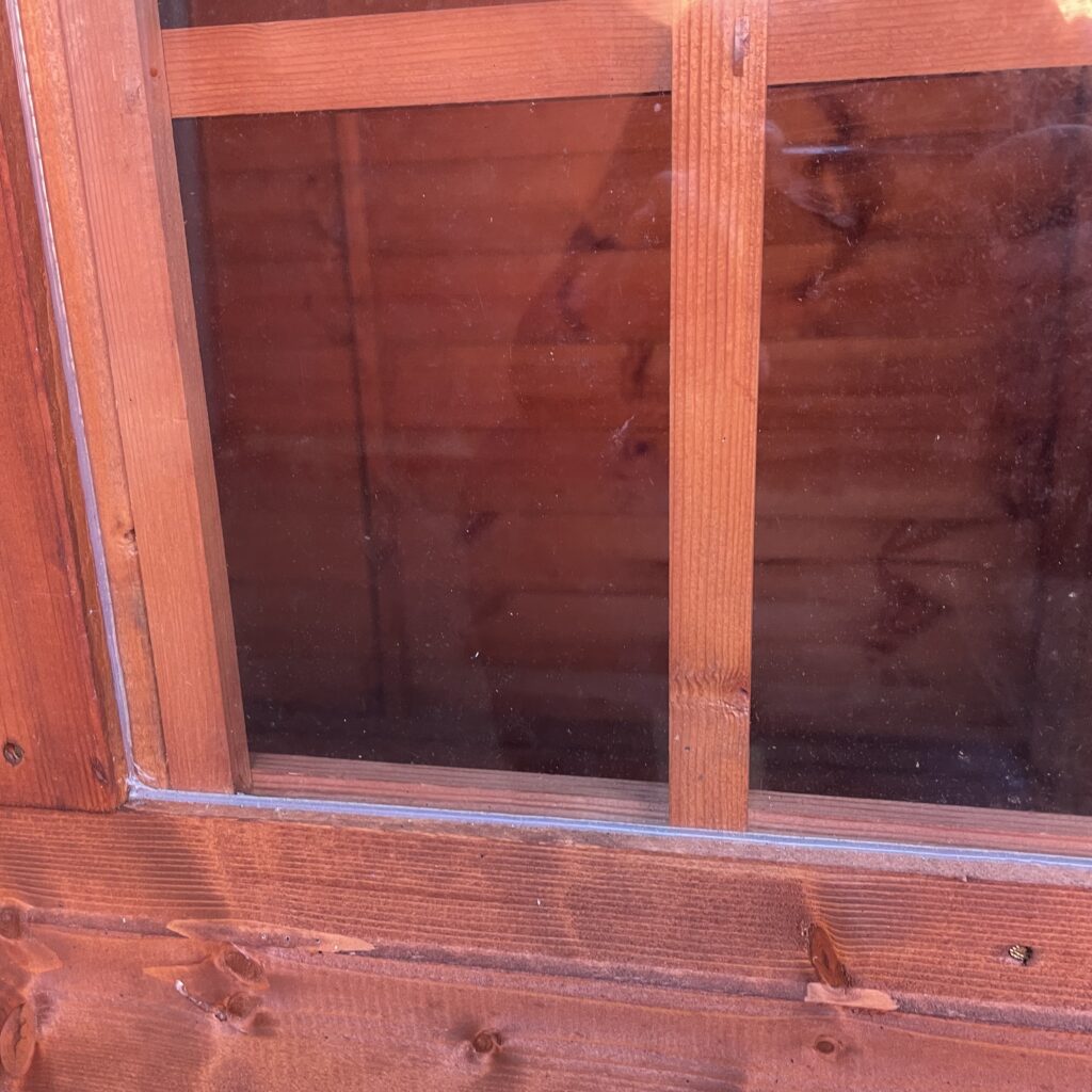 Close-up of a wooden playhouse window with styrene safety glazing