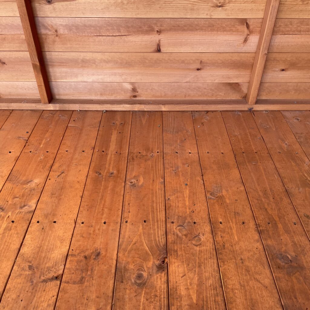 Close-up of a wooden floor in a garden building showing natural wood grain