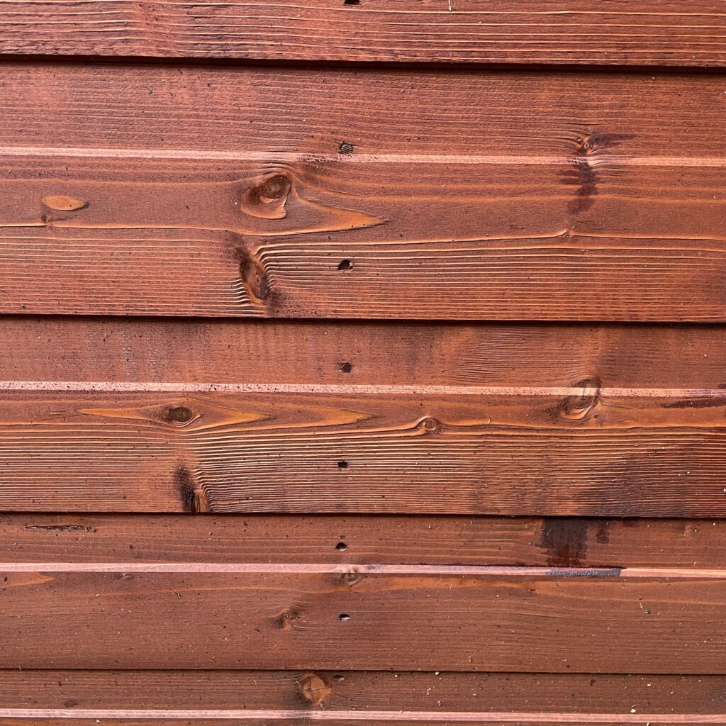 Close-up of red wooden cladding showing natural grain and texture