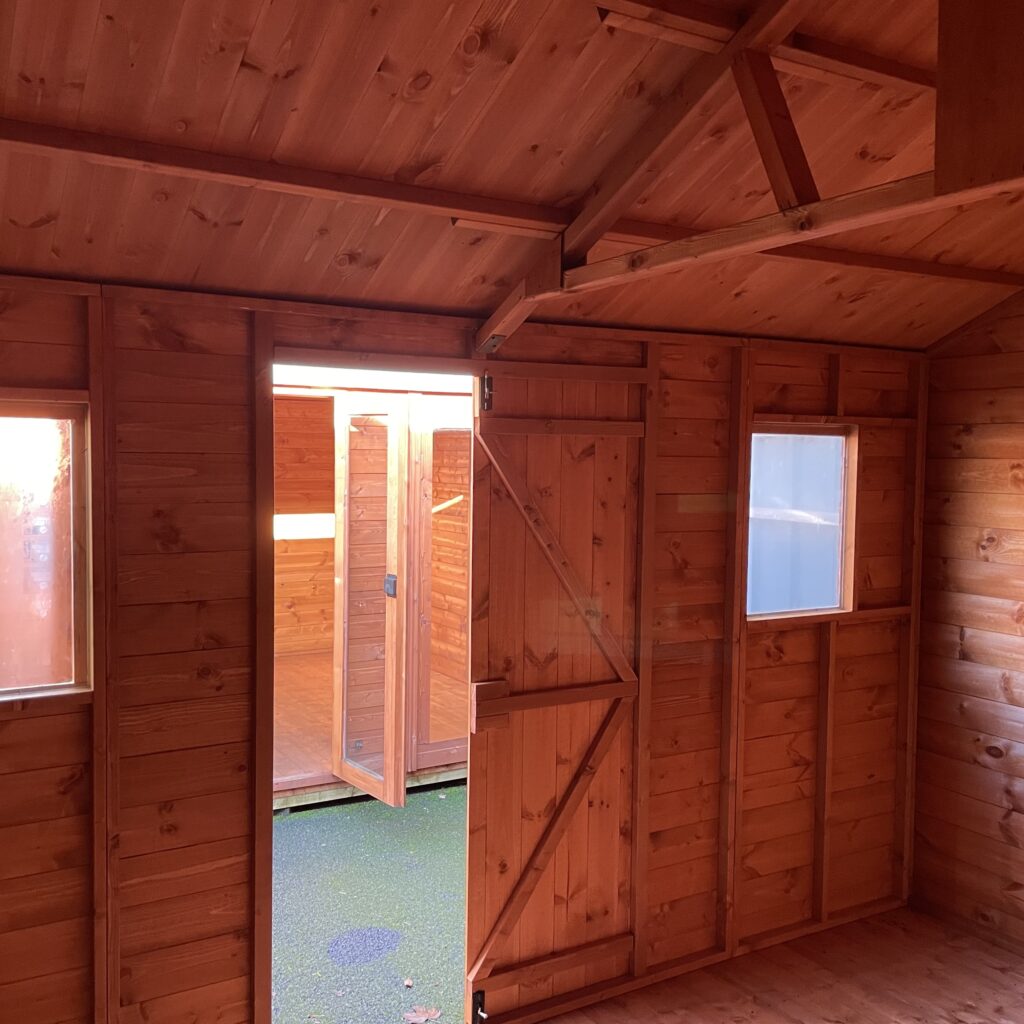 Interior view of a Tiger Workman Apex Shed with wooden walls and door
