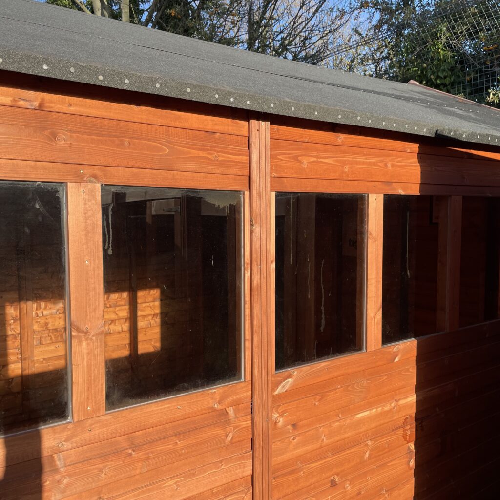 Wooden workshop featuring large fixed windows and an asphalt roof