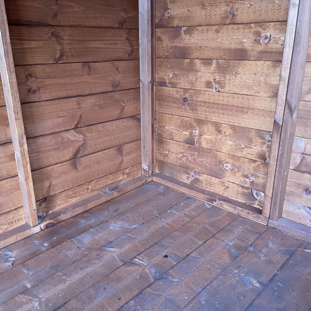 Interior corner of a TigerFlex Shiplap Apex Shed showcasing shiplap cladding and wooden flooring