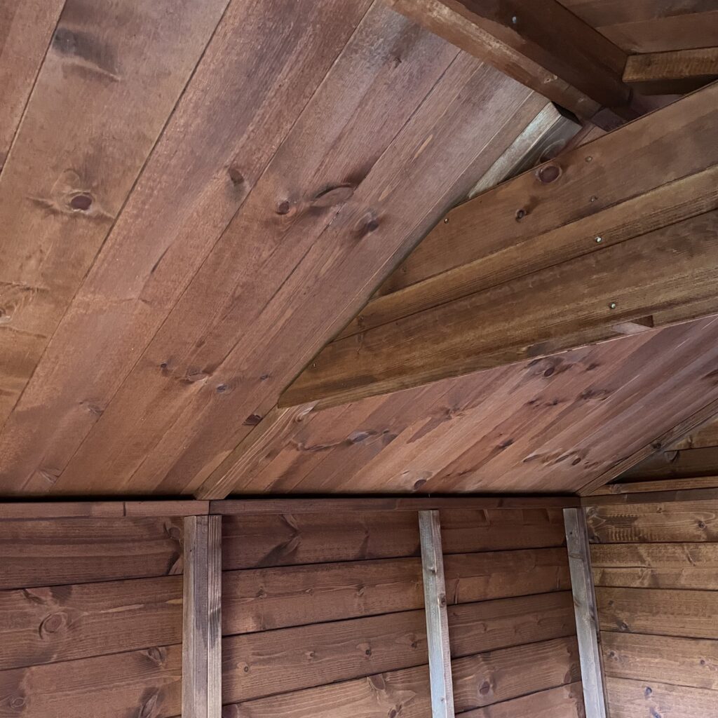 Interior view of a Tiger apex shed showcasing wooden beams and cladding