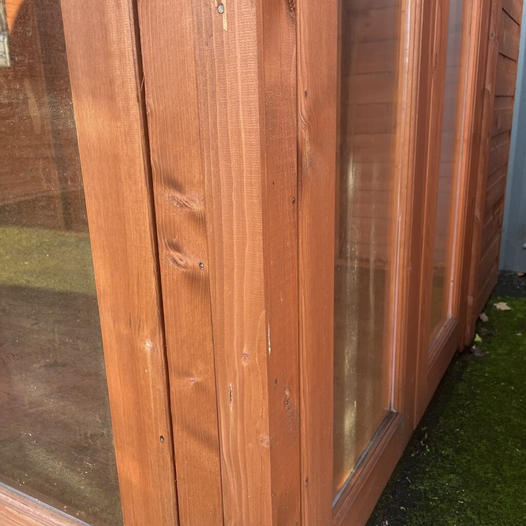 Corner detail of a TigerFlex Shiplap Pent Full Pane Summerhouse highlighting the wood finish and full-pane windows